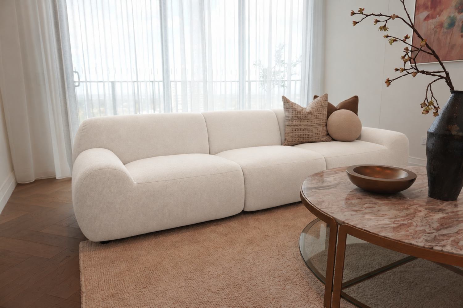 The Freya modular sofa in white, in a light-filled living room beside a marble coffee table
